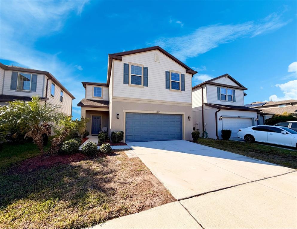 A two-story suburban house with a blue garage door and a concrete driveway — 11415 GREEN HARVEST DRIVE, RIVERVIEW, FL