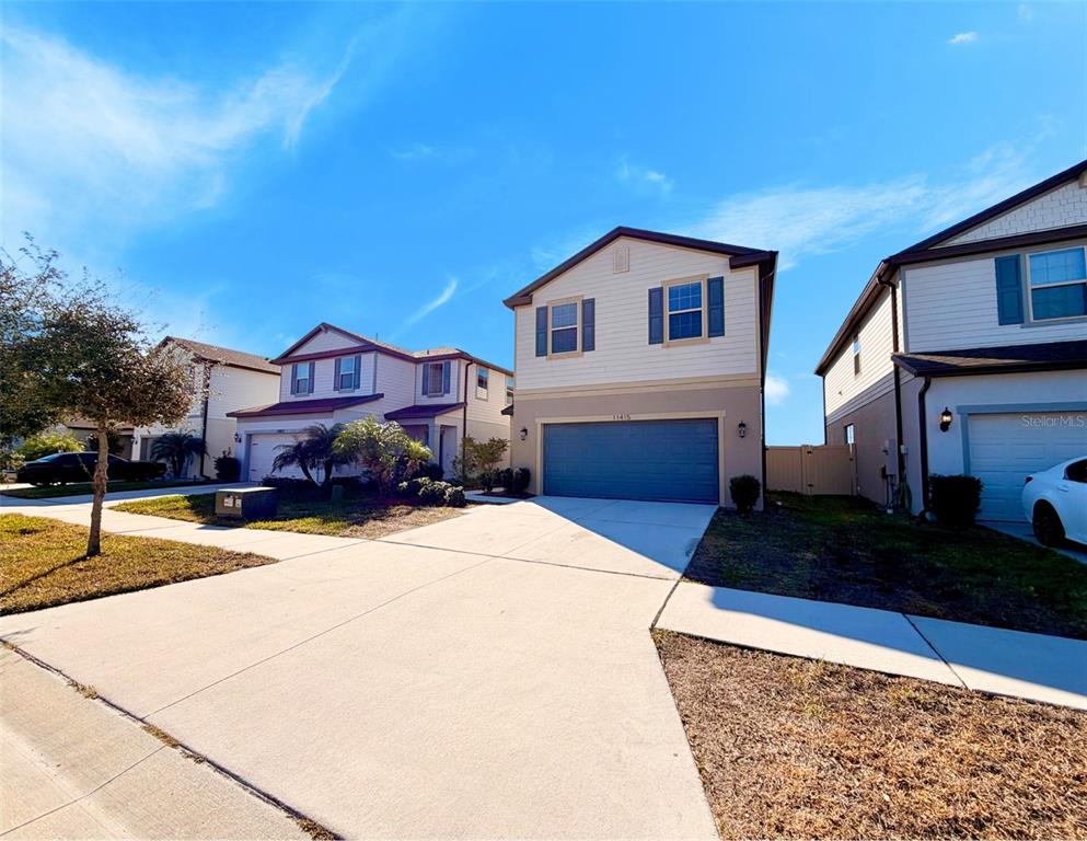A two-story suburban house with a blue garage door and a concrete driveway — 11415 GREEN HARVEST DRIVE, RIVERVIEW, FL