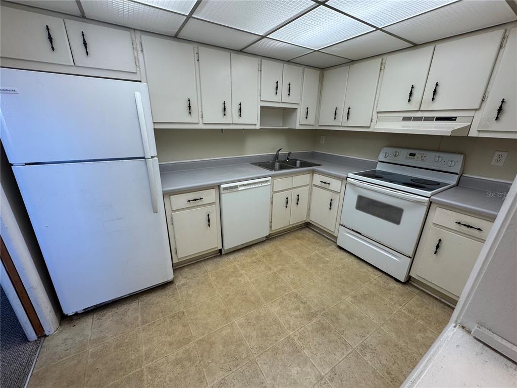 A kitchen features white cabinetry, white appliances, a grey countertop, and a drop ceiling — 245 CENTER ROAD UNIT 211, VENICE, FL
