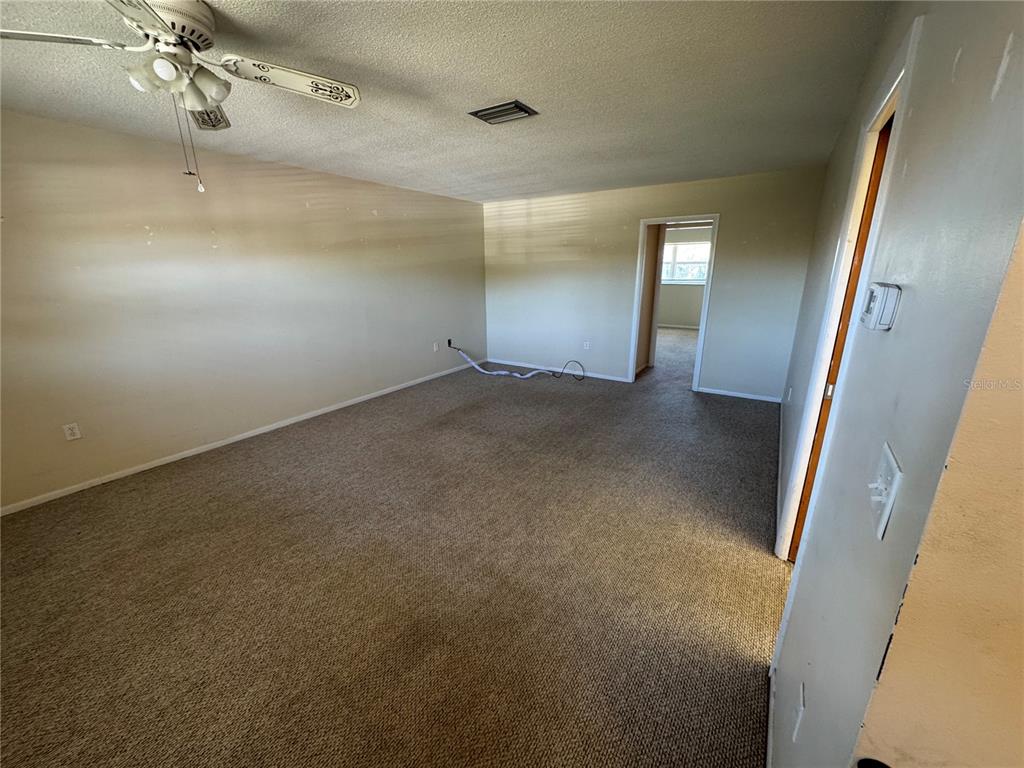 An empty room with beige carpet, a ceiling fan, and a doorway leading to another room — 245 CENTER ROAD UNIT 211, VENICE, FL