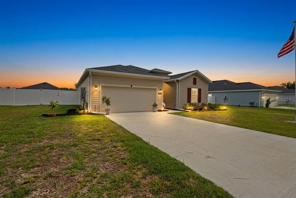 A single-story house with a two-car garage and a concrete driveway at sunset — 560 NW 4TH AVENUE, WILLISTON, FL