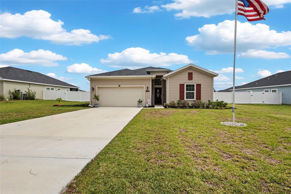 A single-story suburban house with beige siding, a two-car garage, and an American flag pole — 560 NW 4TH AVENUE, WILLISTON, FL