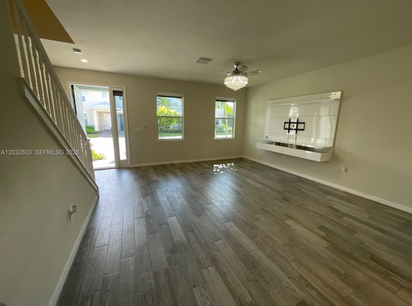 A living room features wood-look tile flooring, a staircase, and a wall-mounted media console — 4920 Eucalyptus Dr # 2, Hollywood FL 33021, HOLLYWOOD, FL