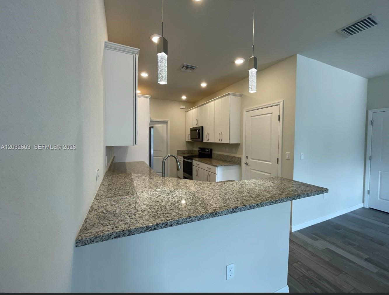 A kitchen features white cabinets, granite countertops, a breakfast bar, and two pendant lights — 4920 Eucalyptus Dr # 2, Hollywood FL 33021, HOLLYWOOD, FL