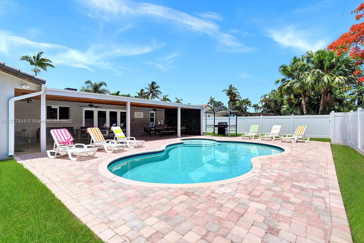 A backyard features a kidney-shaped swimming pool, a paved patio, and several lounge chairs — 1301 Rodman St, Hollywood FL 33019, HOLLYWOOD, FL