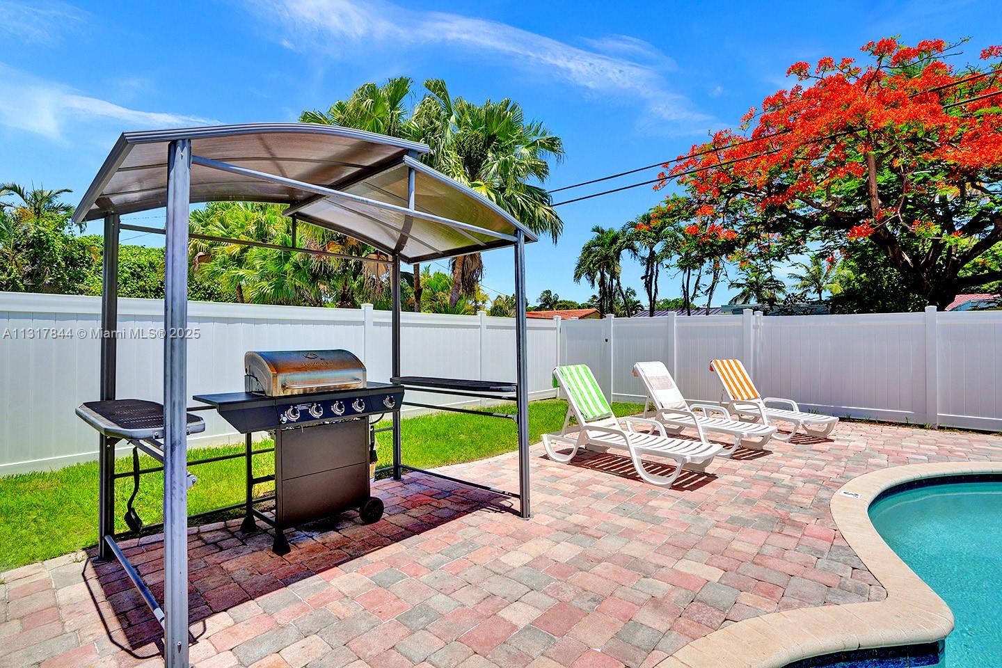 A backyard patio features a grill under a canopy, lounge chairs, and a swimming pool — 1301 Rodman St, Hollywood FL 33019, HOLLYWOOD, FL