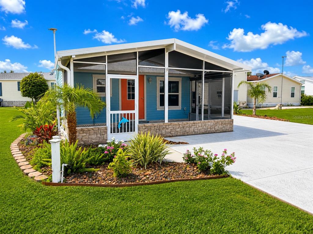 A blue mobile home features a screened-in porch, stone skirting, and a concrete driveway — 5245 ISLAND VIEW CIRCLE N, POLK CITY, FL