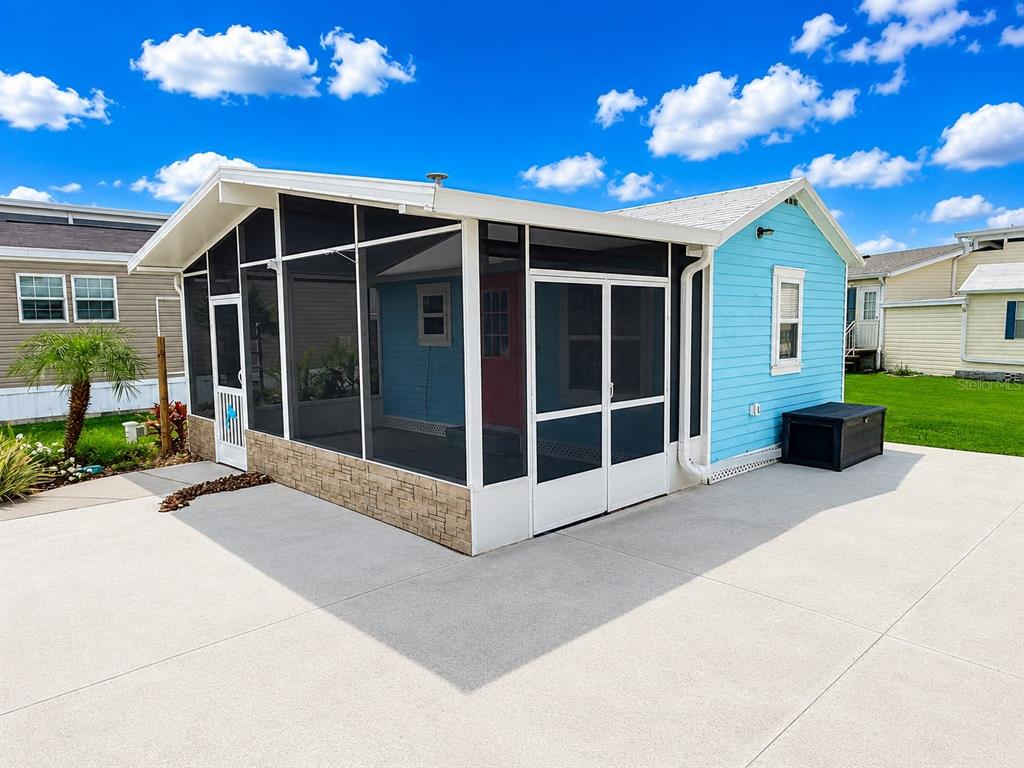 A light blue house features a large screened-in porch with stone-style siding and concrete patio — 5245 ISLAND VIEW CIRCLE N, POLK CITY, FL