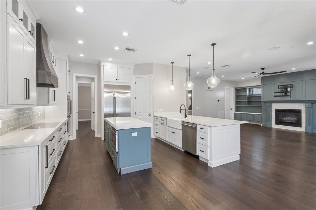 A modern kitchen features white cabinetry, a blue island, stainless steel appliances, and hardwood floors — 5105 W NEPTUNE WAY, TAMPA, FL