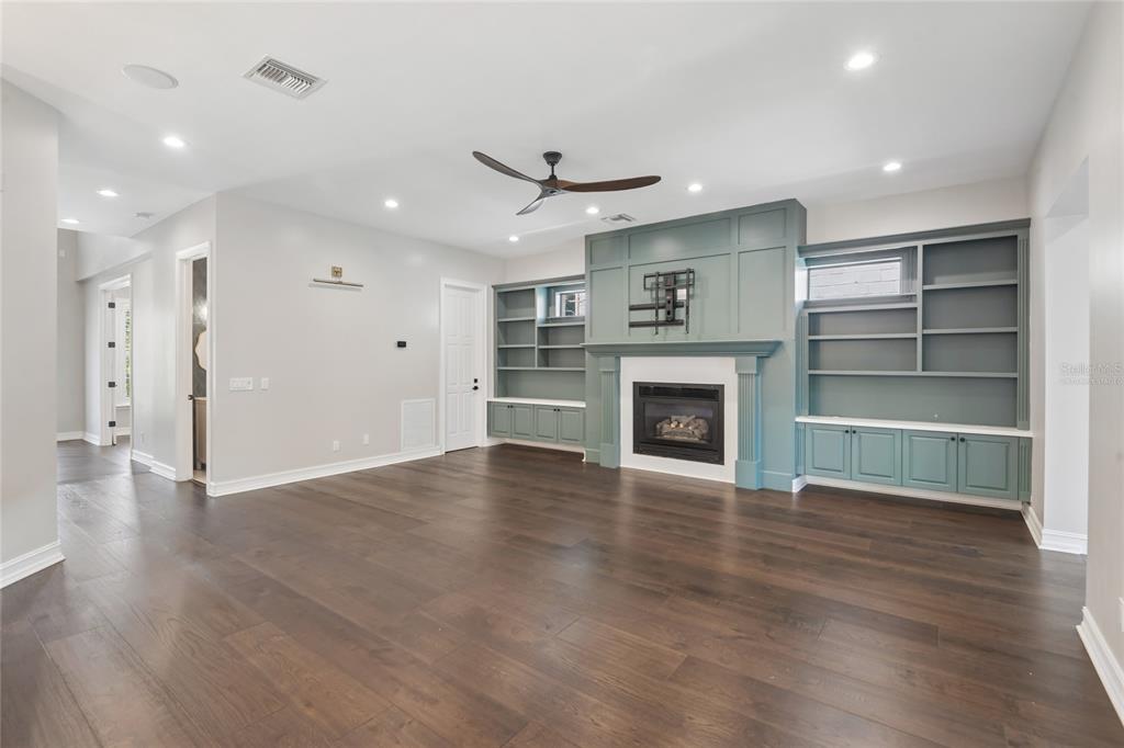 A living room features dark hardwood floors, a fireplace with built-in shelving, and recessed lighting — 5105 W NEPTUNE WAY, TAMPA, FL
