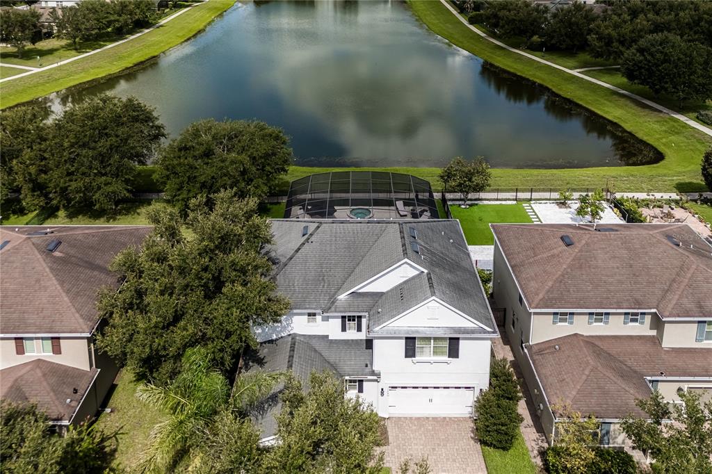 An aerial view shows a two-story house with a pool enclosure overlooking a lake — 11750 CHATEAUBRIAND AVENUE, ORLANDO, FL