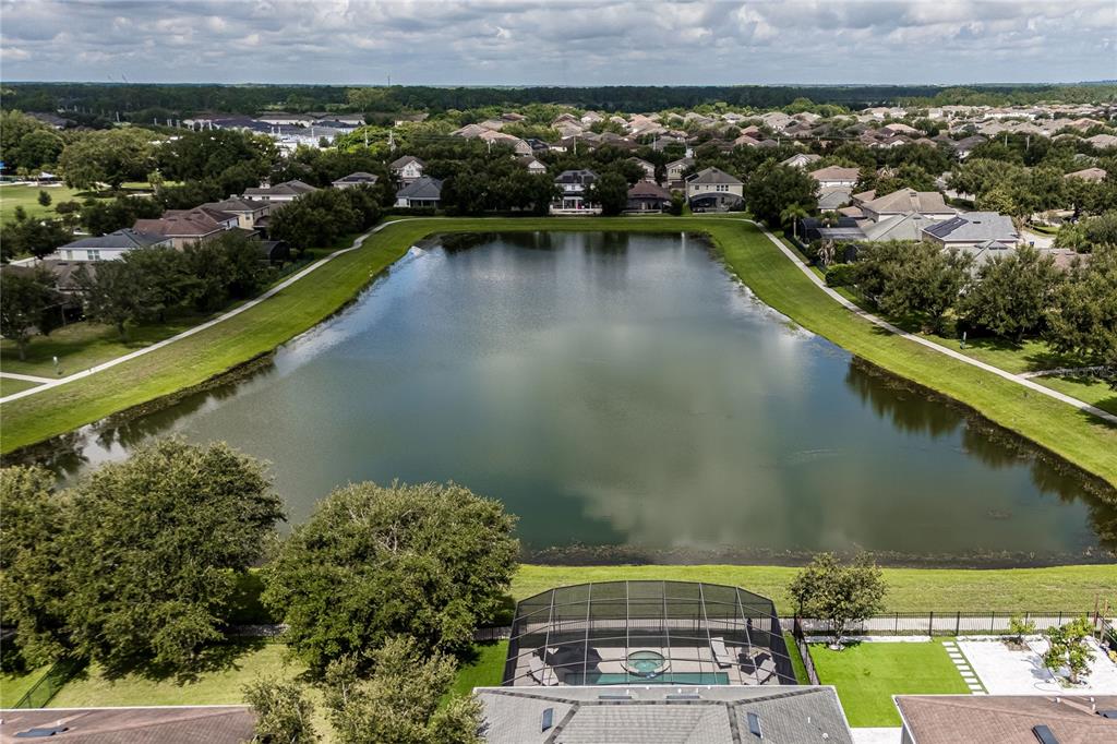 An aerial view shows a house with a screened pool overlooking a large retention pond — 11750 CHATEAUBRIAND AVENUE, ORLANDO, FL