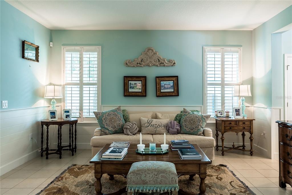 A living room features light blue walls, white wainscoting, a beige sofa, and two windows — 11750 CHATEAUBRIAND AVENUE, ORLANDO, FL