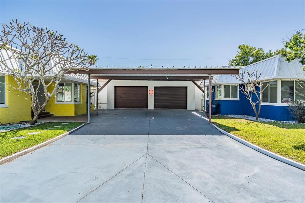 A concrete driveway leads to a two-car carport situated between two single-story residential buildings — 14060 MIRAMAR AVENUE, ST PETERSBURG, FL