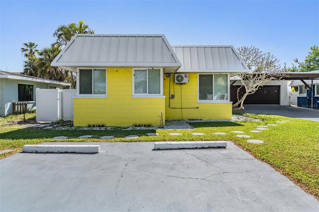 A bright yellow single-story building with a metal awning and a paved parking area — 14060 MIRAMAR AVENUE, ST PETERSBURG, FL