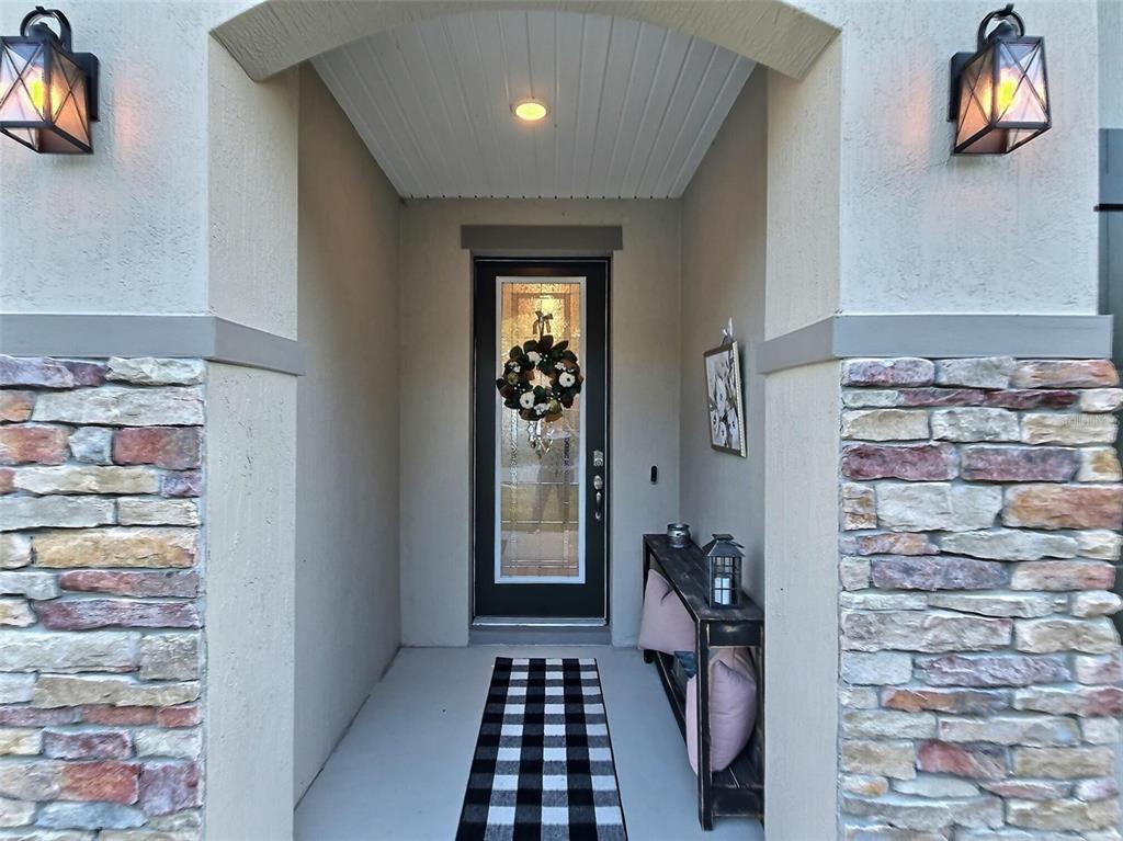 A covered entryway features stone pillars, two wall sconces, and a glass-paneled front door — 2 PAT PLACE, PALM COAST, FL