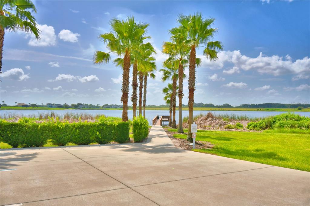 A concrete path leads through palm trees toward a wooden dock on a lake — 361 ADAMS VIEW LANE, AUBURNDALE, FL