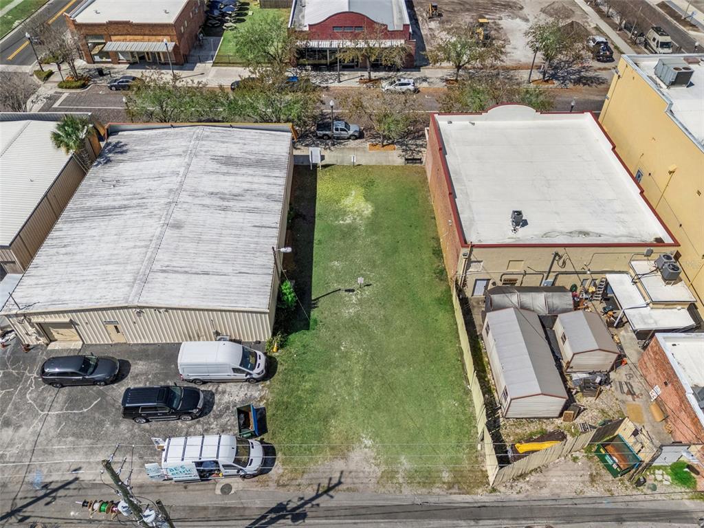 An aerial view shows a vacant grassy lot situated between two commercial buildings — 215 MAGNOLIA AVENUE, SANFORD, FL