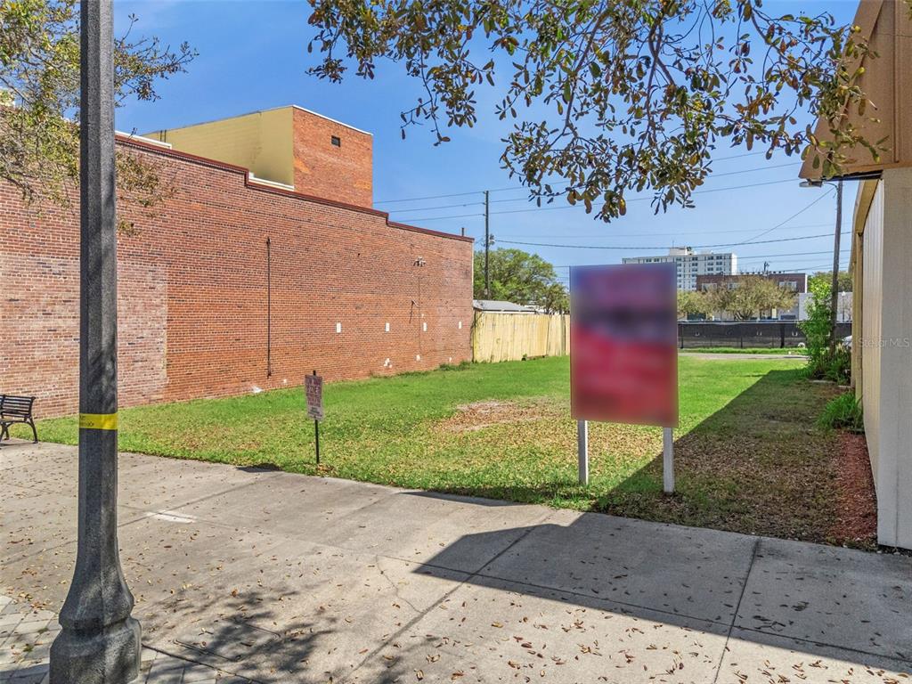 A vacant urban lot sits between two buildings with a sign in the foreground — 215 MAGNOLIA AVENUE, SANFORD, FL