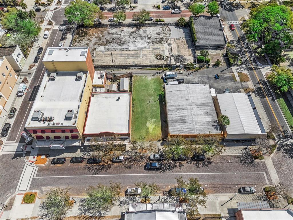 An aerial view shows a vacant lot situated between two commercial buildings along a paved street — 215 MAGNOLIA AVENUE, SANFORD, FL