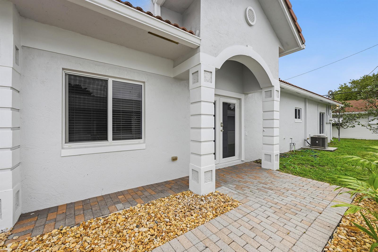 A white house exterior features a paved walkway, a covered entryway, and a large window — 911 NE 12th Avenue, Pompano Beach FL 33060, POMPANO BEACH, FL