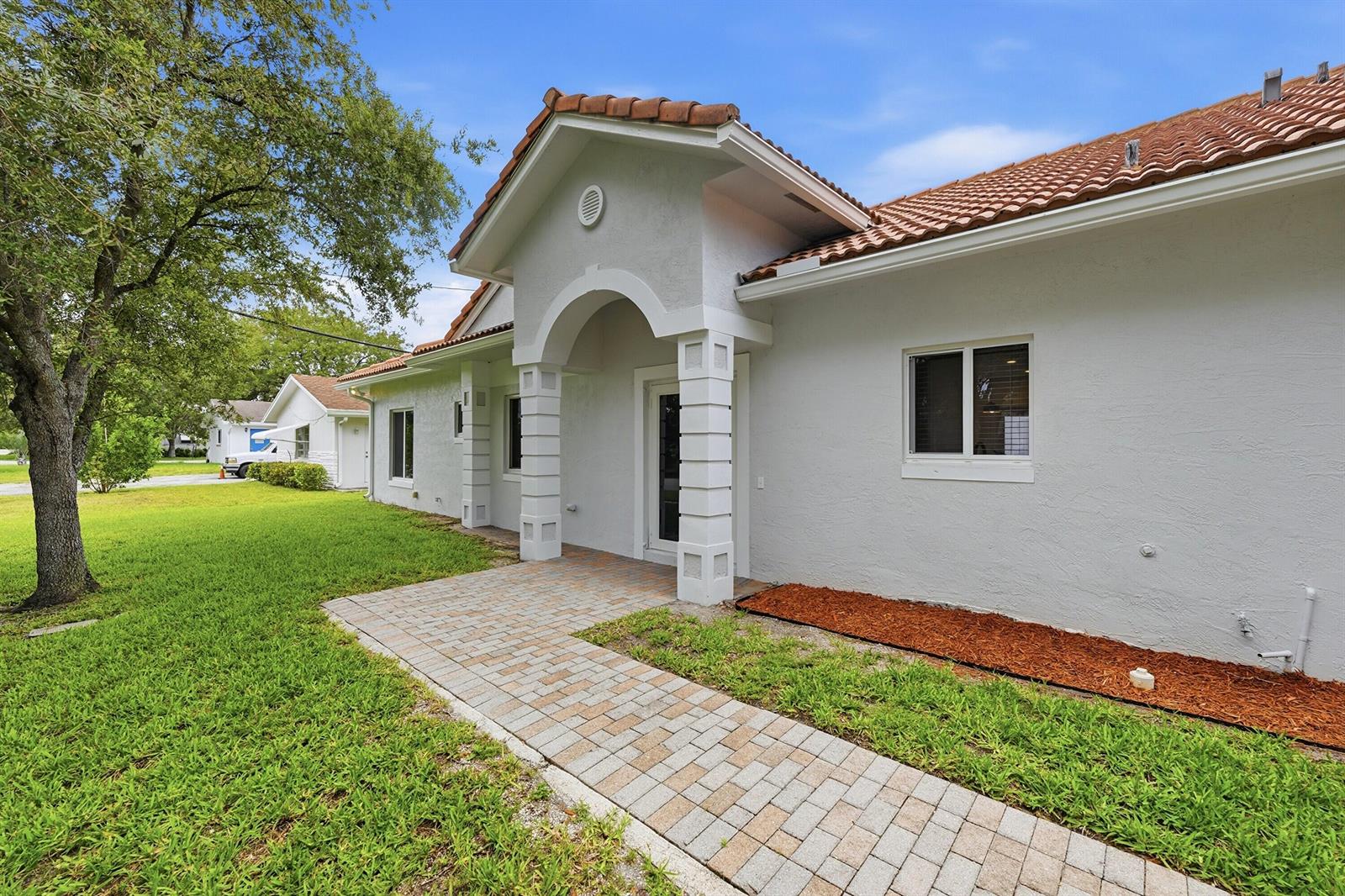 A white stucco house with a tiled roof features a brick walkway and arched entryway — 911 NE 12th Avenue, Pompano Beach FL 33060, POMPANO BEACH, FL