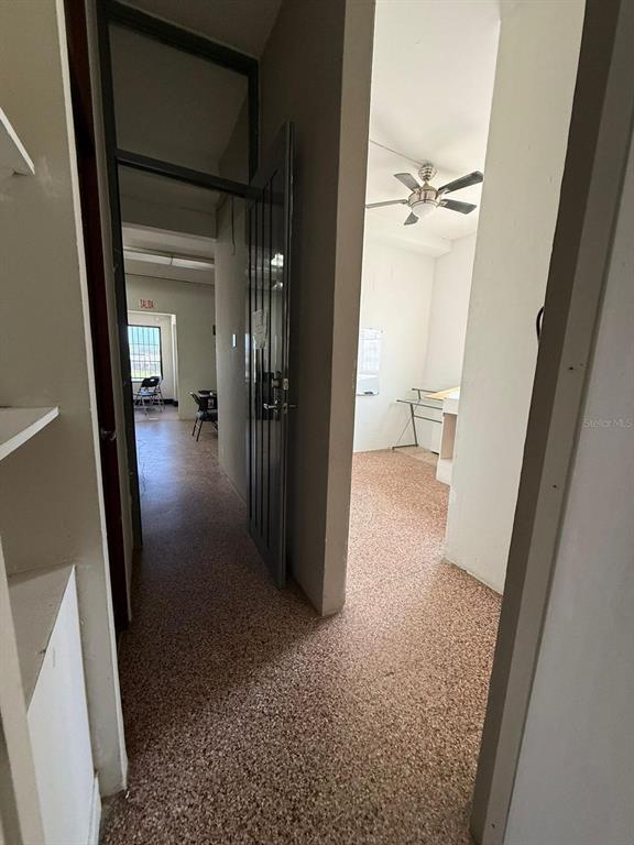 A hallway with speckled flooring leads to an open room featuring a ceiling fan — 9 URB. LOS ÁNGELES MARGINAL BLQ WA, CAROLINA, PR