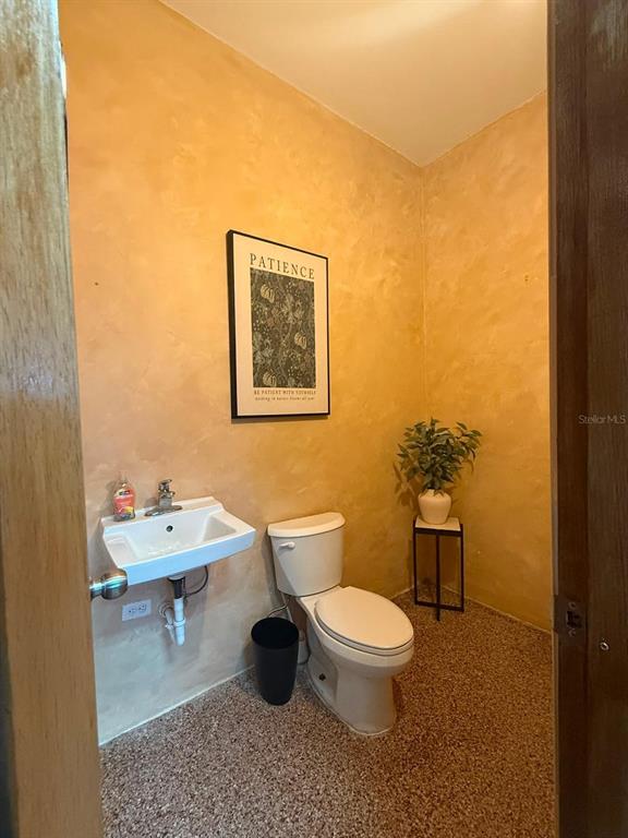 A small bathroom features a wall-mounted sink, a toilet, and textured yellow walls — 9 URB. LOS ÁNGELES MARGINAL BLQ WA, CAROLINA, PR