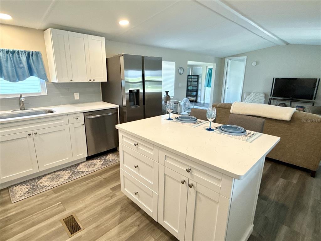 A kitchen with white cabinets, a center island, and stainless steel appliances opens to a living area — 217 MOUNT PINEY AVENUE NE UNIT 286, ST PETERSBURG, FL
