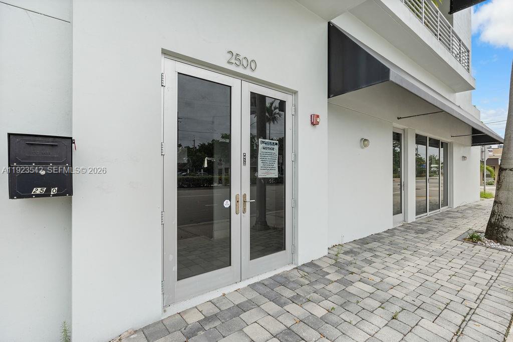 The exterior of a white commercial building features double glass doors and a mailbox — 2500 Wilton Dr, Wilton Manors FL 33305, WILTON MANORS, FL