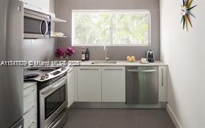 A modern kitchen features stainless steel appliances, white cabinetry, and a window above the sink — 1816 Meridian Ave # 4, Miami Beach FL 33139, MIAMI BEACH, FL