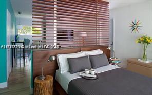 A bedroom features a wooden slat room divider, a bed with gray bedding, and wood flooring — 1816 Meridian Ave # 4, Miami Beach FL 33139, MIAMI BEACH, FL