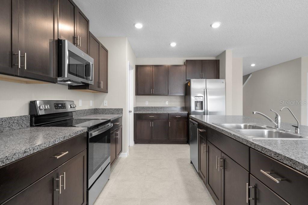 A kitchen with dark wood cabinets, granite countertops, and stainless steel appliances — 7227 RONNIE GARDENS COURT, TAMPA, FL