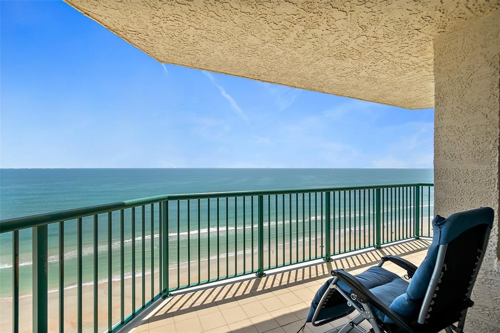 A balcony with a green metal railing overlooks the ocean and a sandy beach — 3315 S ATLANTIC AVENUE UNIT 1605, DAYTONA BEACH SHORES, FL