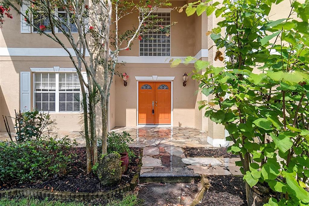 A tan two-story house features orange double front doors and a stone walkway — 3 ZORRO COURT, PALM COAST, FL