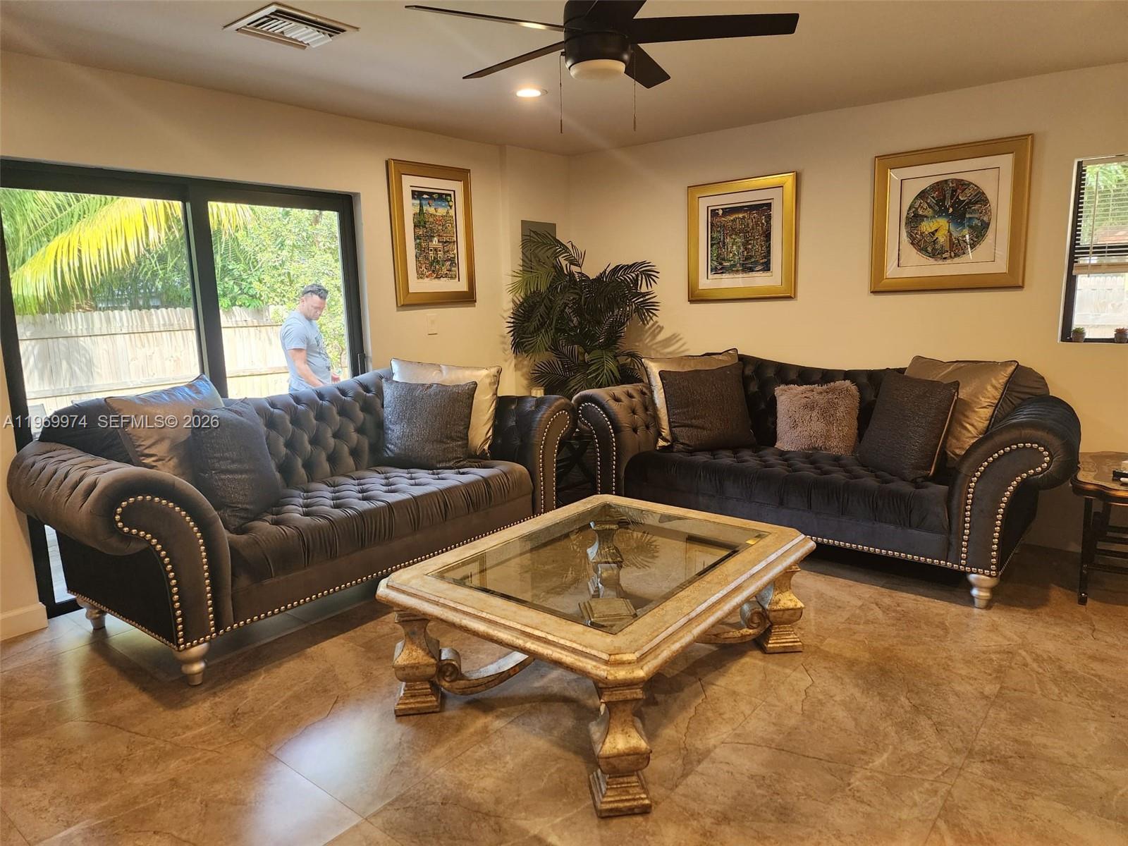 A living room features two tufted charcoal sofas, a glass-topped coffee table, and tiled floors — 413 SW 10th St, Delray Beach FL 33444, DELRAY BEACH, FL