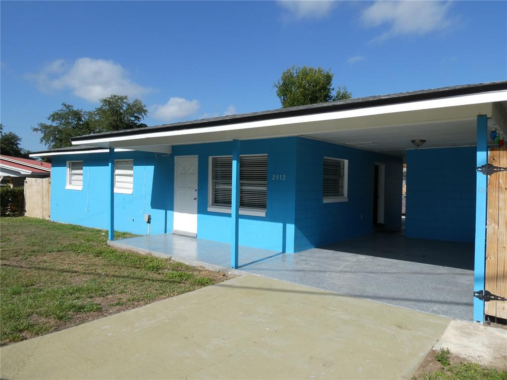 A bright blue single-story house features a front porch and an attached carport — 2912 DUDLEY DRIVE, BARTOW, FL