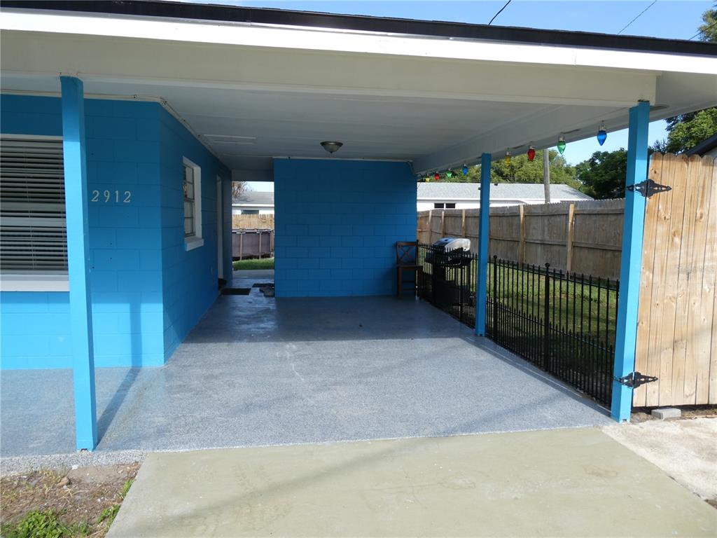 A bright blue house features a covered carport with a speckled concrete floor — 2912 DUDLEY DRIVE, BARTOW, FL