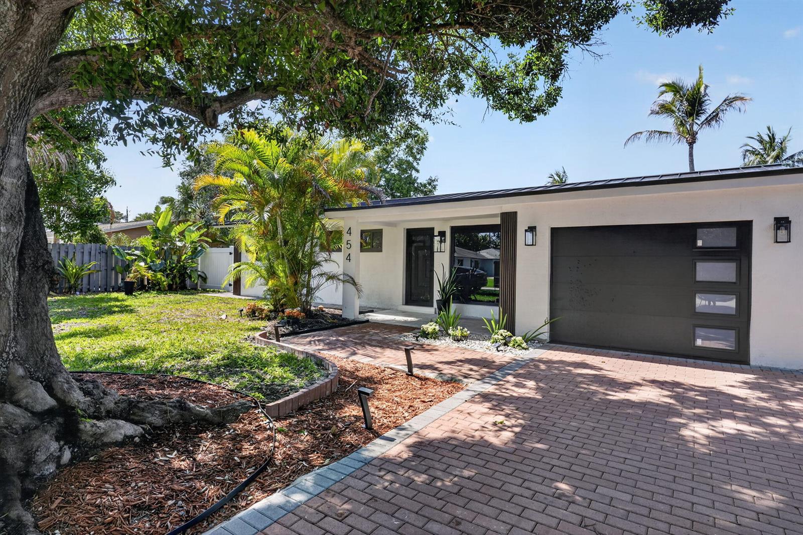 A single-story house with a white exterior, dark garage door, and brick driveway — 454 Dover Road, Jupiter FL 33469, JUPITER, FL