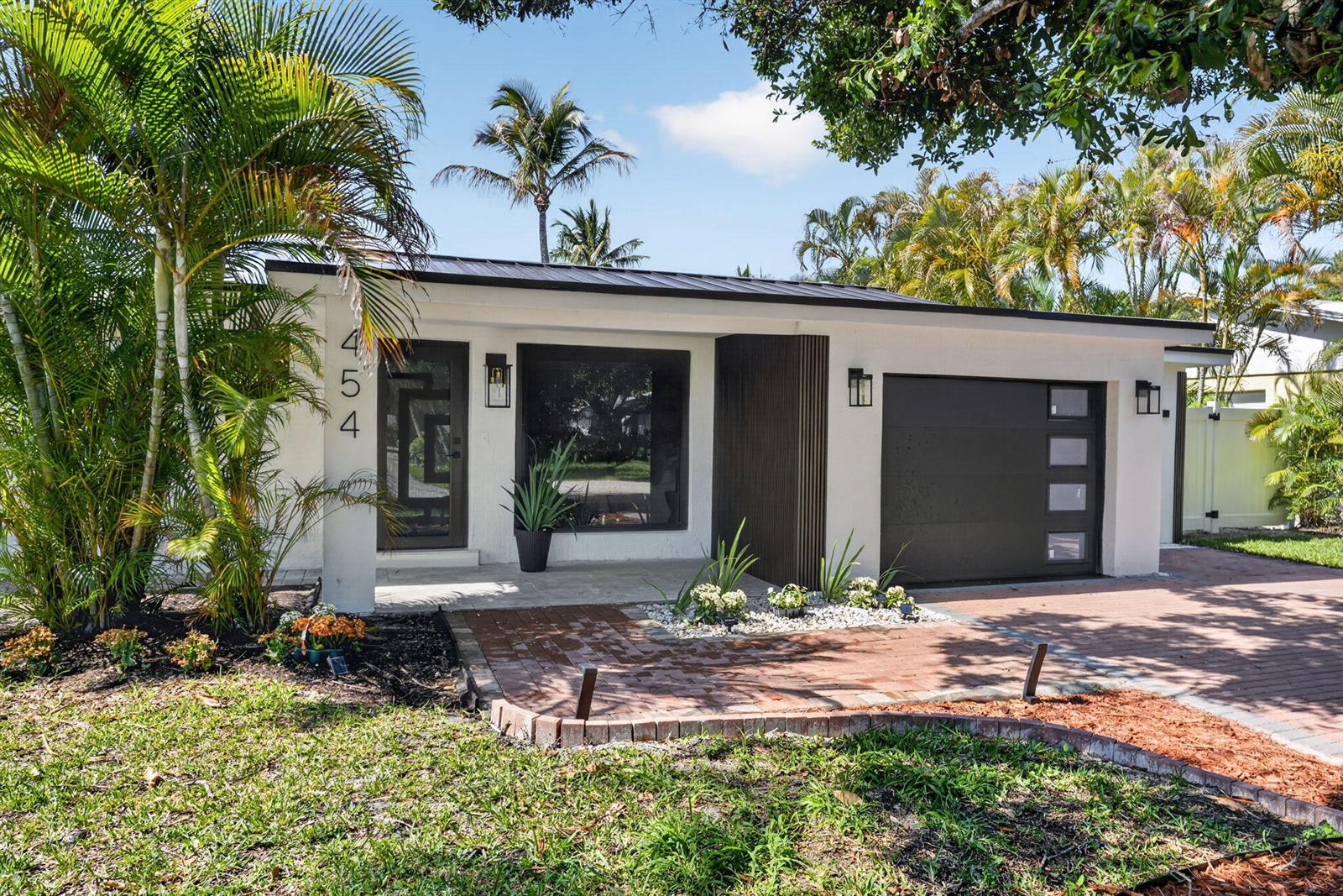 A single-story house with a white exterior, dark garage door, and a brick driveway — 454 Dover Road, Jupiter FL 33469, JUPITER, FL