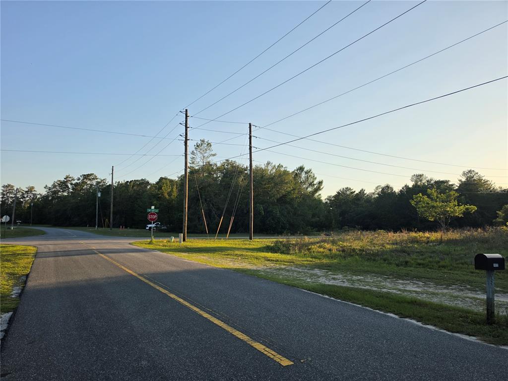 A paved road leads to a rural intersection with a stop sign and utility poles — SW 18TH AVE RIVER, OCALA, FL