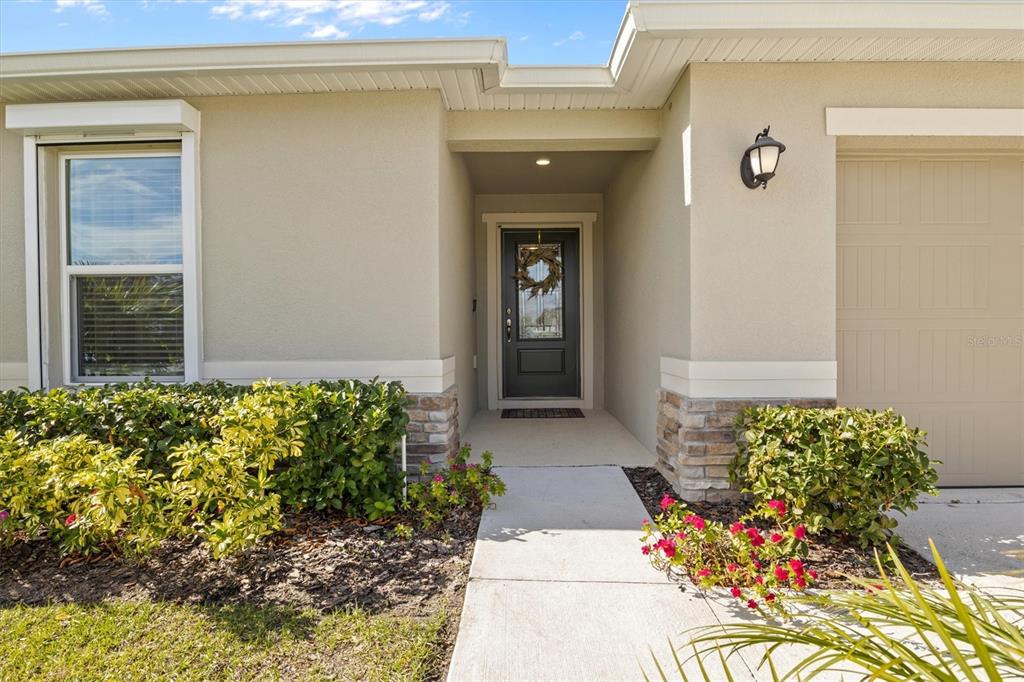 The exterior of a house features a front door, a garage, and landscaped bushes — 1591 MATTIE POINTE PLACE, AUBURNDALE, FL