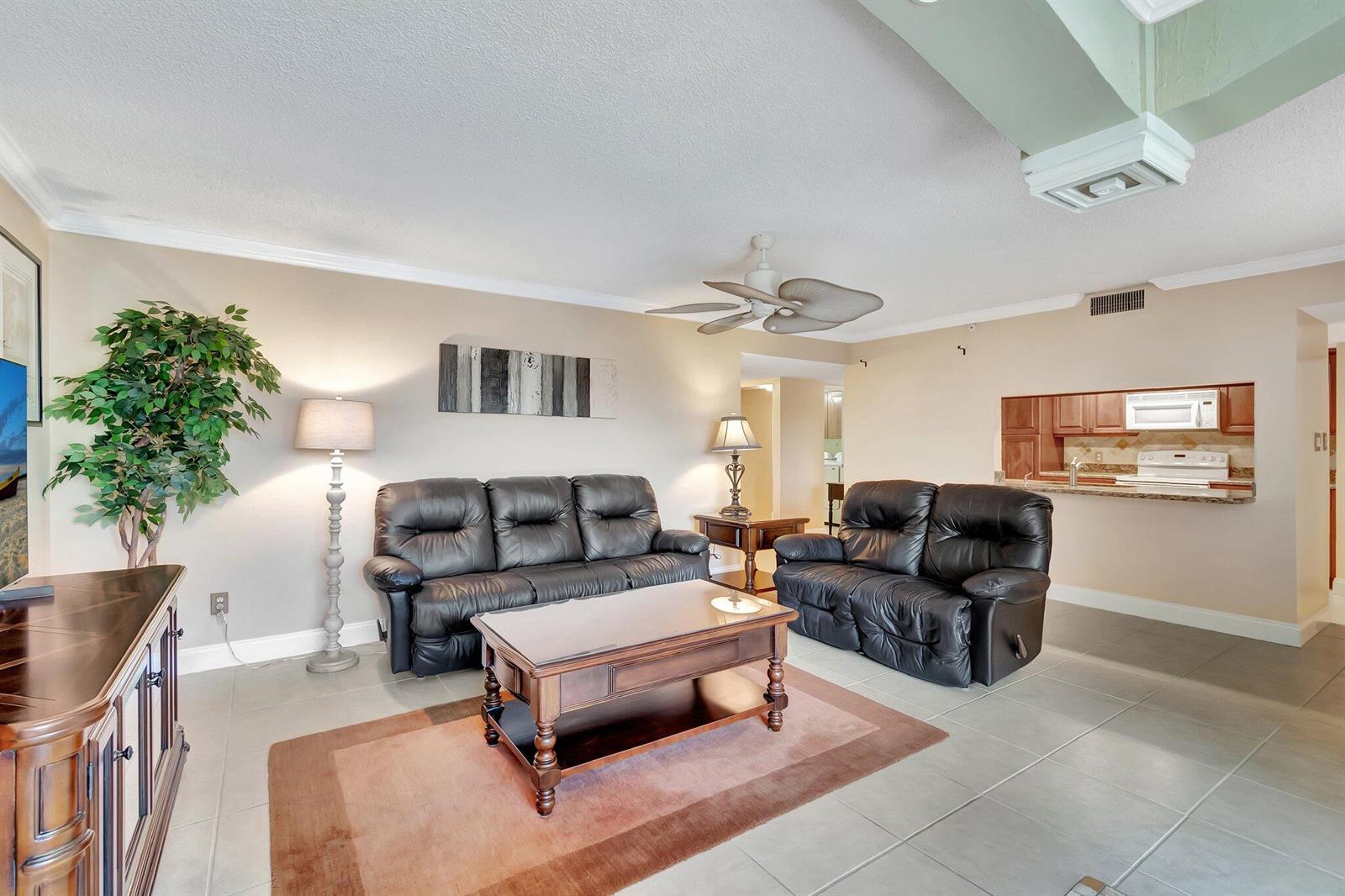 A living room features a black leather sofa and loveseat, a coffee table, and tile flooring — 1915 Lavers Circle # 303, Delray Beach FL 33444, DELRAY BEACH, FL