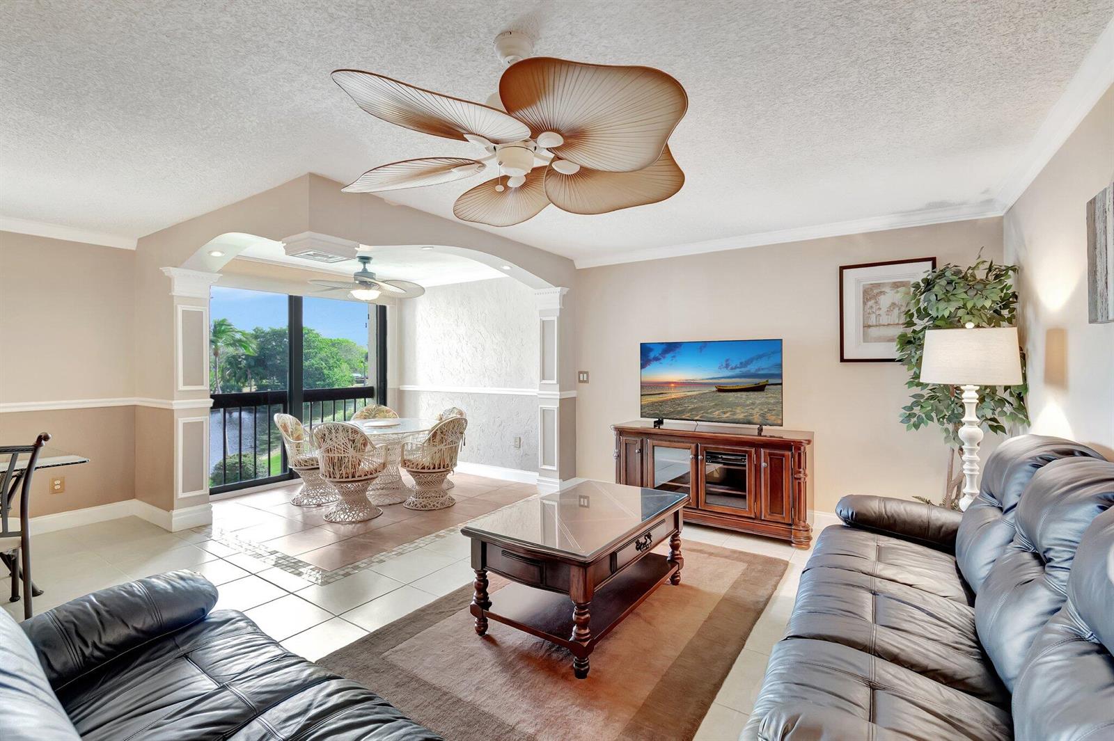 A living room with a ceiling fan, leather sofas, and a dining area overlooking water — 1915 Lavers Circle # 303, Delray Beach FL 33444, DELRAY BEACH, FL