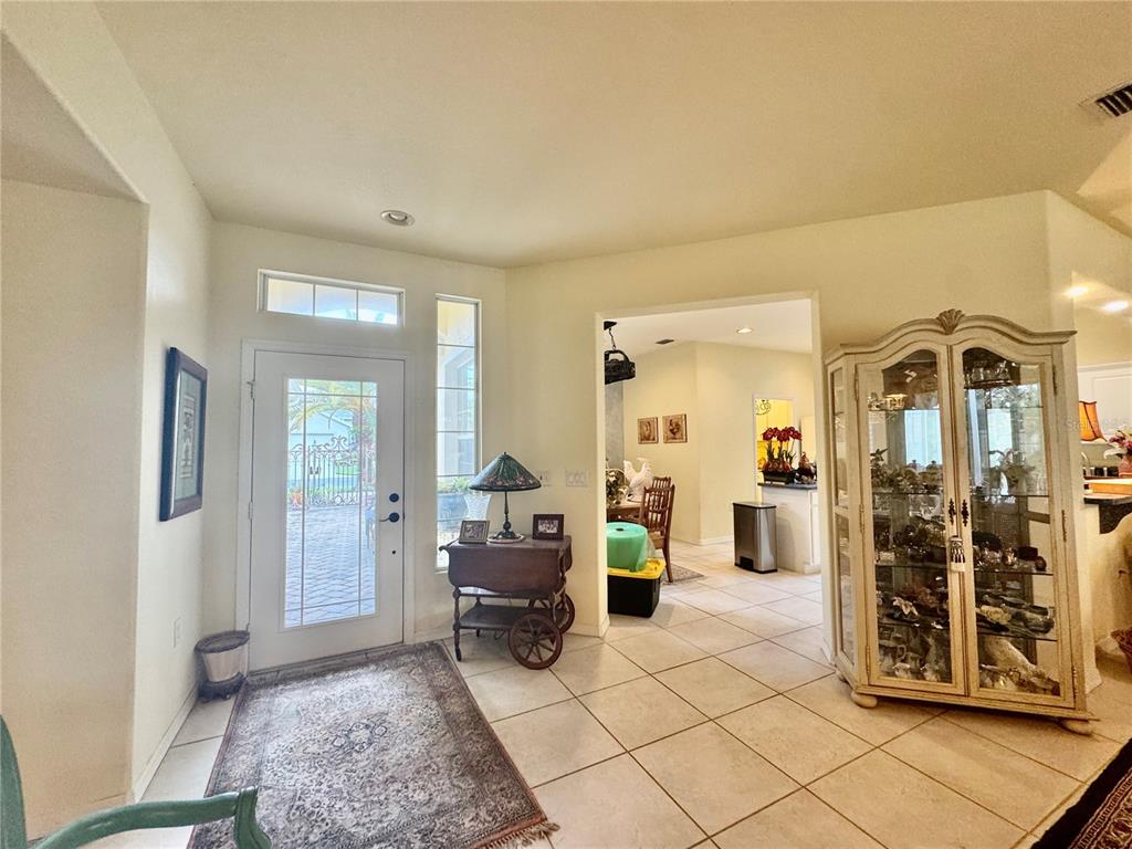An entryway with tile flooring, a glass-paneled front door, and a decorative curio cabinet — 12491 SE 91ST TERRACE ROAD, SUMMERFIELD, FL