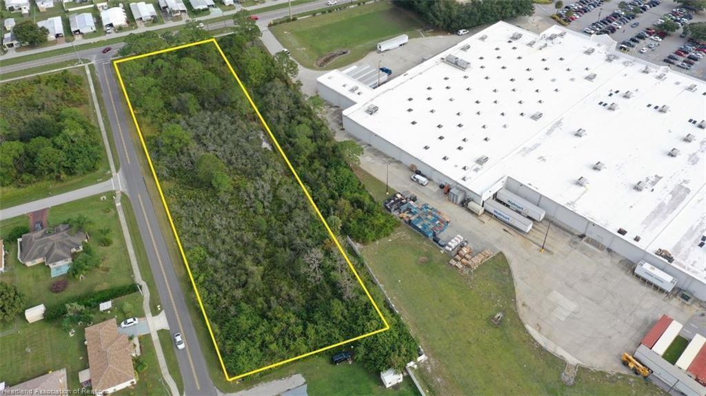 An aerial view shows a rectangular, wooded vacant lot situated next to a large commercial building — 3237 Schumacher Road, Sebring FL 33872, SEBRING, FL