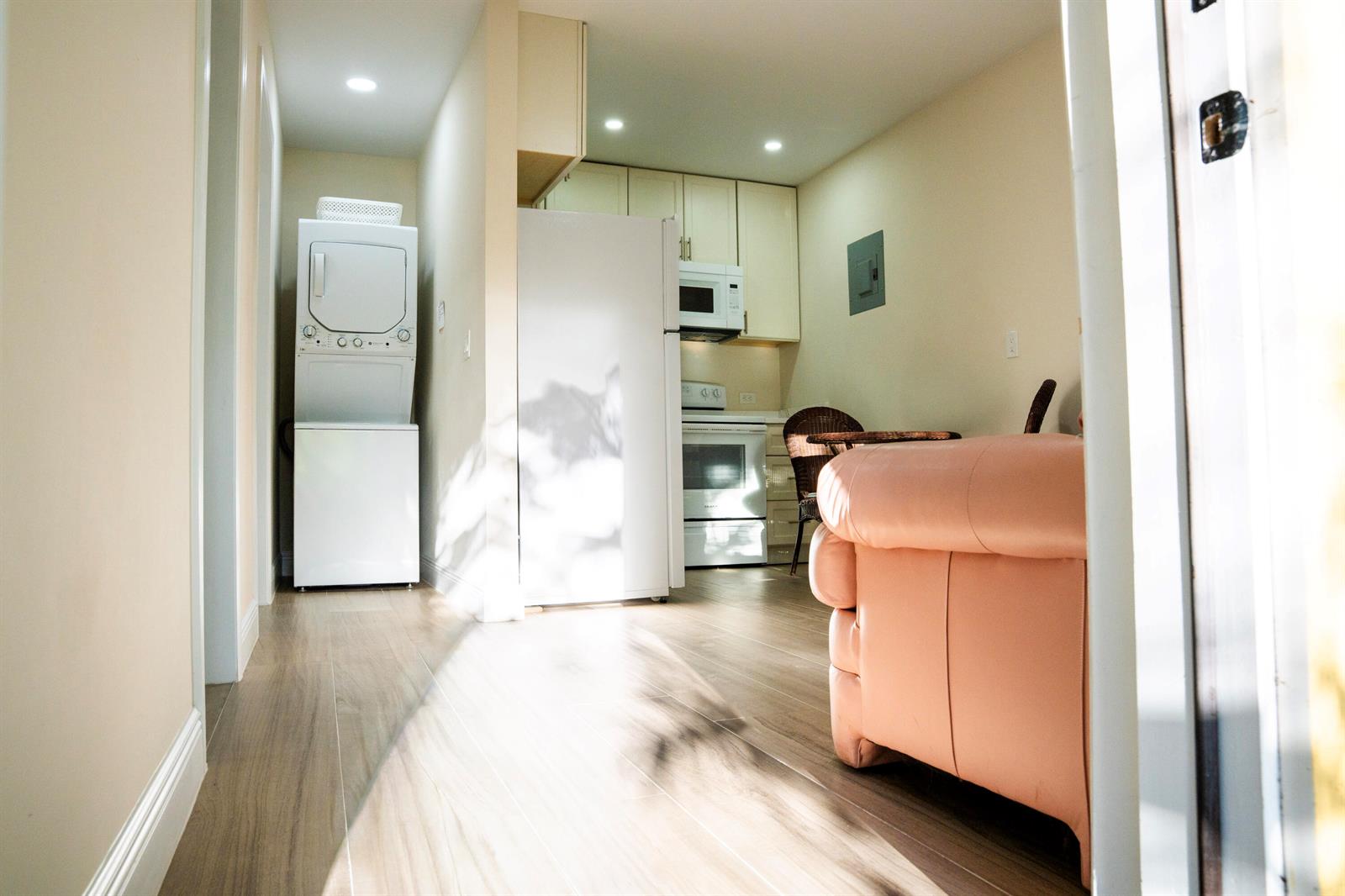 A view of a kitchen and laundry area with a stacked washer-dryer and light flooring — 13075 Marcella Boulevard Unit 2, FL 33470, FL