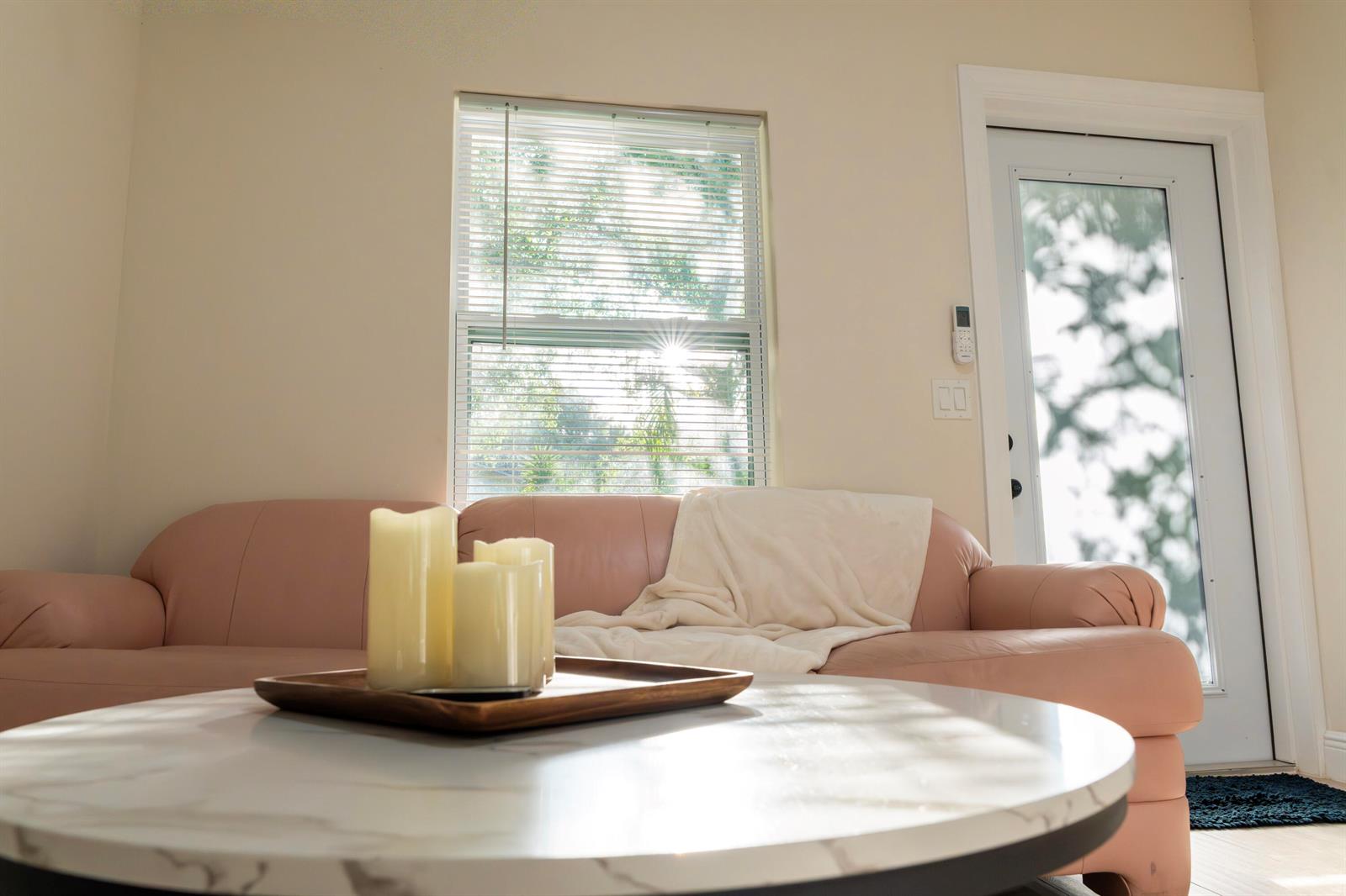 A living room features a pink sofa, a marble coffee table, and a glass-paned door — 13075 Marcella Boulevard Unit 2, FL 33470, FL