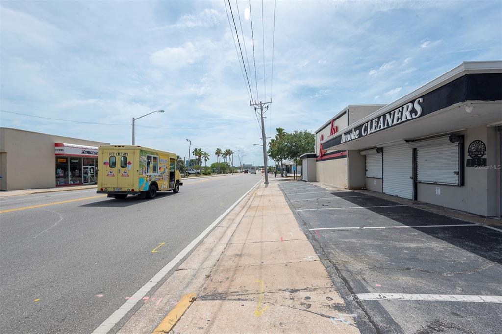 An exterior view shows a street with an ice cream truck and a commercial building — 133 MAIN STREET E, DAYTONA BEACH, FL