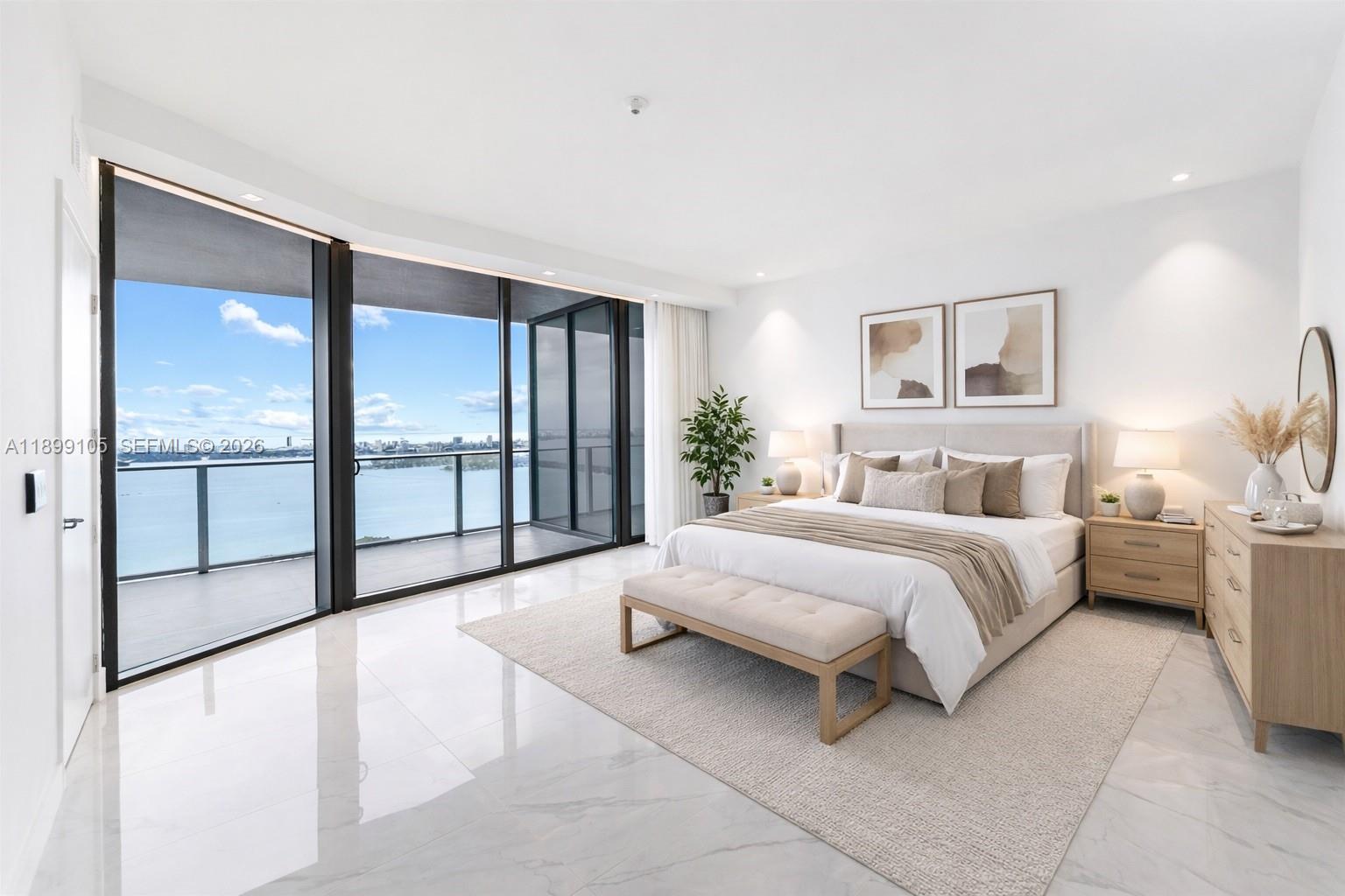 A modern bedroom features white marble floors, a king bed, and floor-to-ceiling windows overlooking water — 700 NE 24th St # 5401, Miami FL 33137, MIAMI, FL